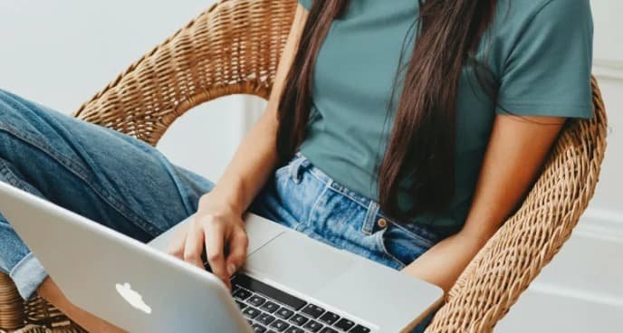 Student sitting in a wicker chair using a laptop